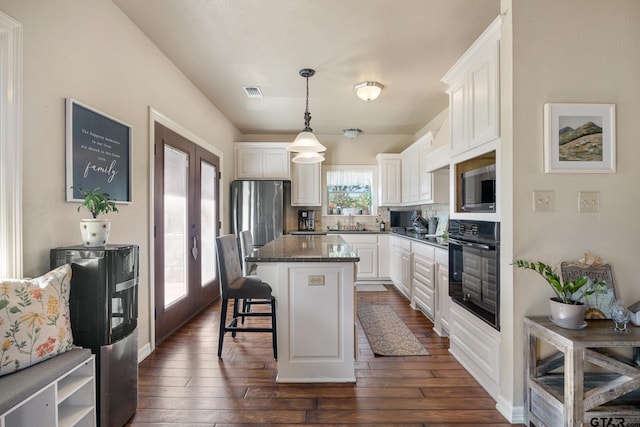 kitchen featuring stainless steel appliances, white cabinetry, a kitchen bar, a center island, and french doors