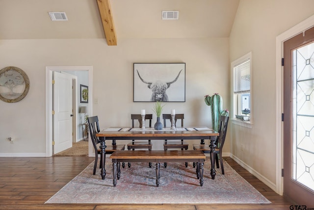 dining room with dark wood-type flooring, lofted ceiling with beams, and a healthy amount of sunlight