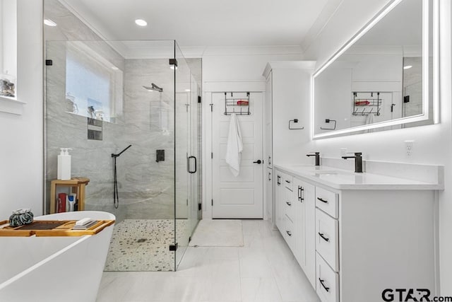 full bath featuring vanity, a freestanding tub, a stall shower, crown molding, and marble finish floor