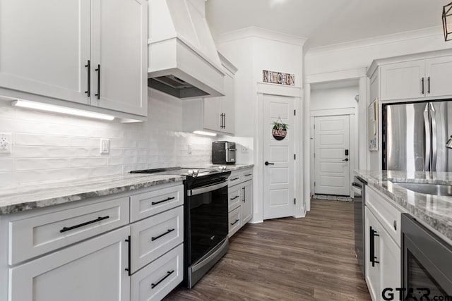 kitchen with premium range hood, dark wood-type flooring, ornamental molding, appliances with stainless steel finishes, and decorative backsplash