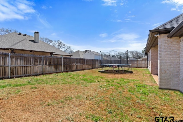 view of yard featuring a trampoline and a fenced backyard