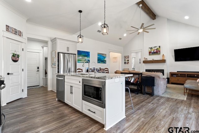 kitchen featuring beam ceiling, a fireplace, dark wood-style flooring, stainless steel appliances, and open floor plan