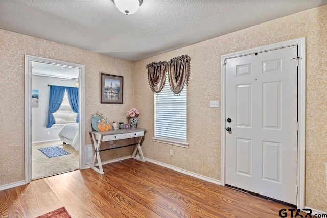 foyer entrance featuring ceiling fan, hardwood / wood-style floors, and a textured ceiling