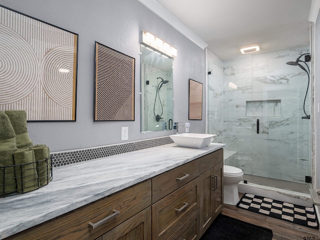 bathroom with vanity, a textured ceiling, hardwood / wood-style flooring, toilet, and a shower with shower door