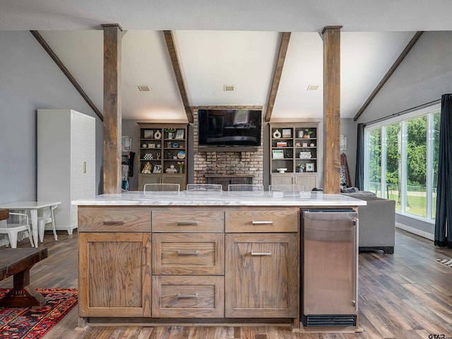 kitchen with light stone countertops, dark hardwood / wood-style floors, beam ceiling, and a kitchen island