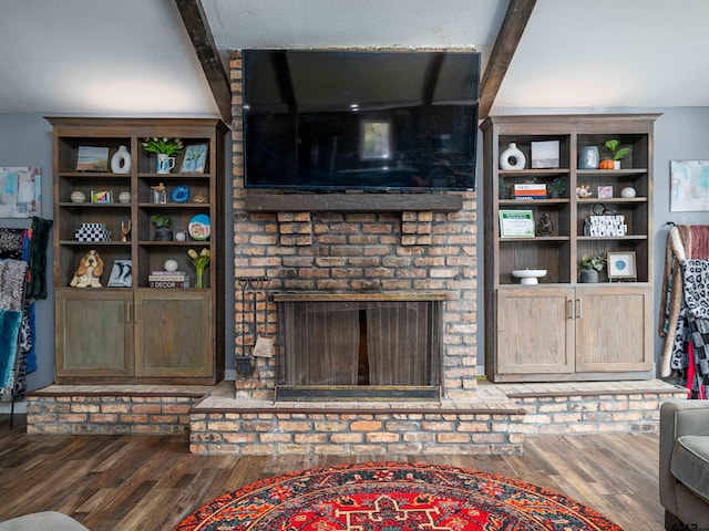 living room featuring beamed ceiling, dark hardwood / wood-style floors, and a fireplace