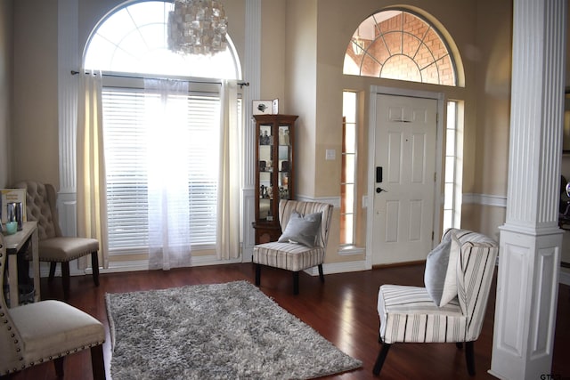 foyer entrance featuring a high ceiling, a chandelier, dark hardwood / wood-style flooring, and decorative columns