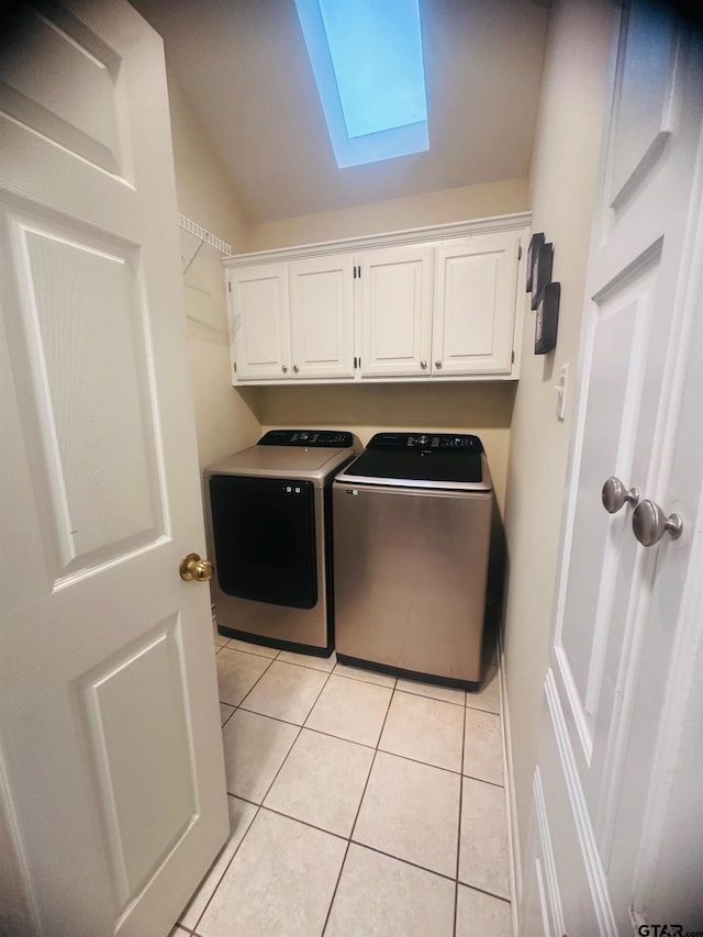 clothes washing area featuring cabinets, washing machine and dryer, light tile patterned flooring, and a skylight