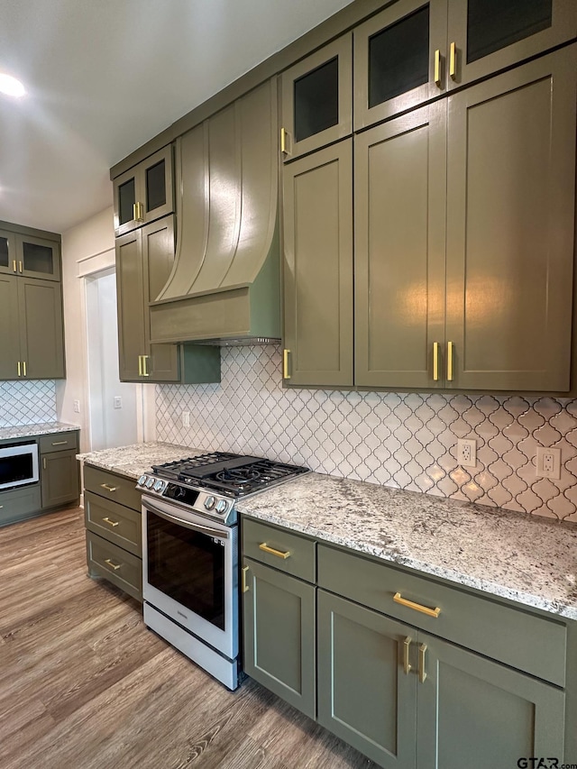 12301 Harlon, Flint, TX 75762 - kitchen with stainless steel gas range, green cabinetry, light wood finished floors, and backsplash
