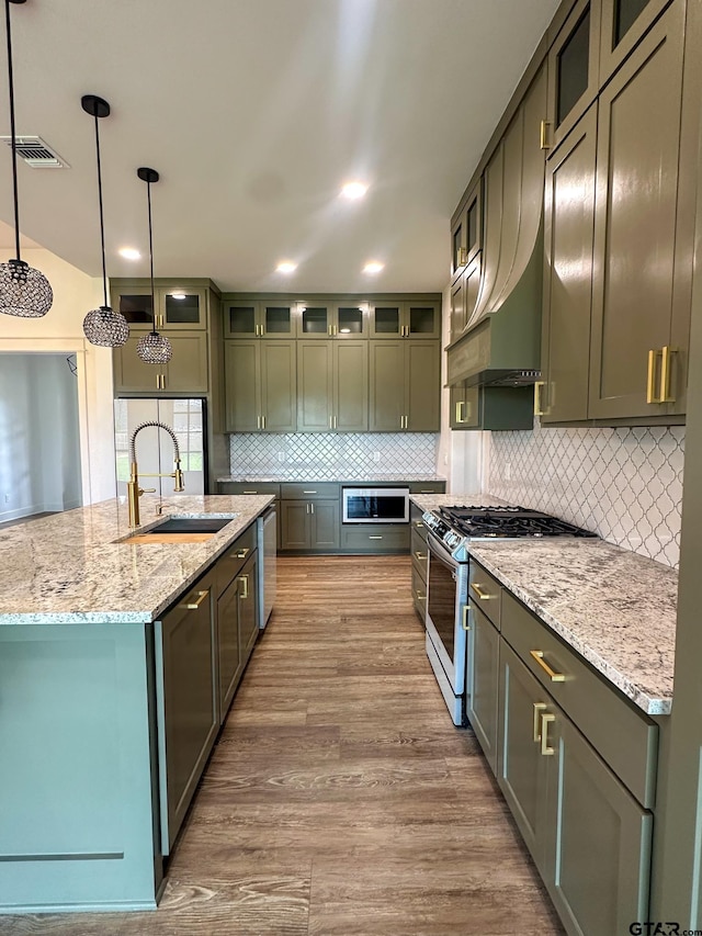 12301 Harlon, Flint, TX 75762 - kitchen with stainless steel gas stove, wood finished floors, decorative backsplash, a kitchen island with sink, and light stone countertops