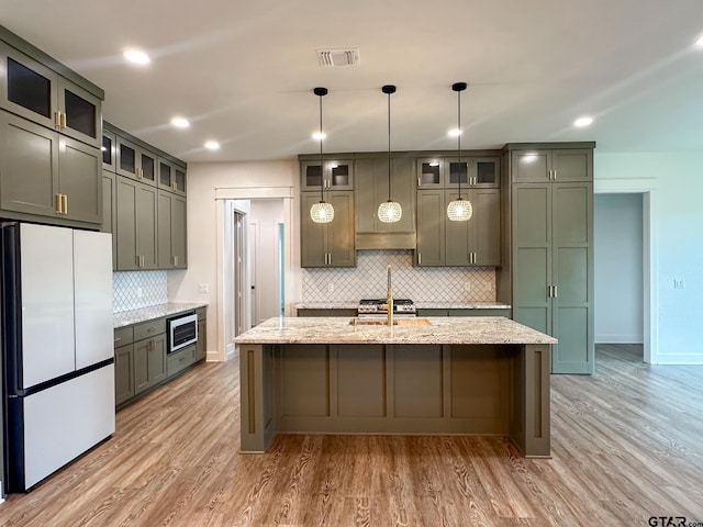 12301 Harlon, Flint, TX 75762 - kitchen with freestanding refrigerator, decorative backsplash, light wood finished floors, light stone counters, and stainless steel microwave