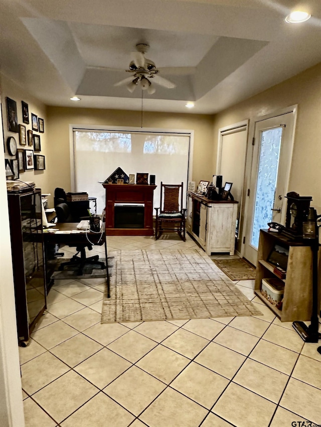 tiled office with a tray ceiling, ceiling fan, and a healthy amount of sunlight