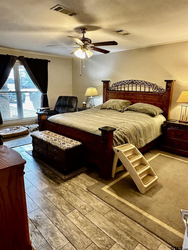 bedroom featuring wood-type flooring, a textured ceiling, ceiling fan, and ornamental molding