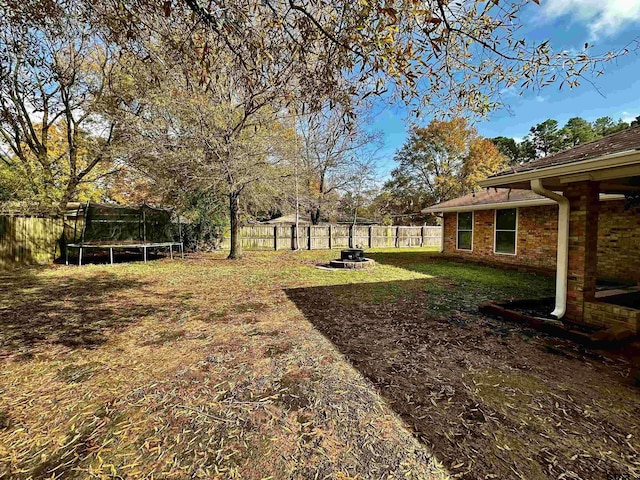 view of yard featuring a fire pit and a trampoline