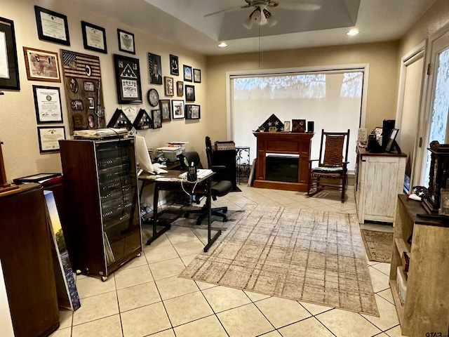 tiled home office featuring a raised ceiling and ceiling fan