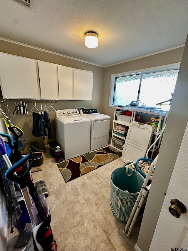 laundry room featuring cabinets, ornamental molding, a textured ceiling, washing machine and clothes dryer, and light tile patterned flooring