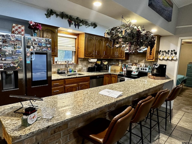 kitchen with sink, a kitchen breakfast bar, tasteful backsplash, light tile patterned floors, and appliances with stainless steel finishes