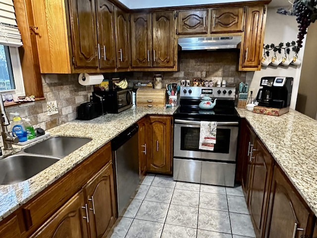 kitchen with backsplash, light stone counters, light tile patterned floors, and stainless steel appliances