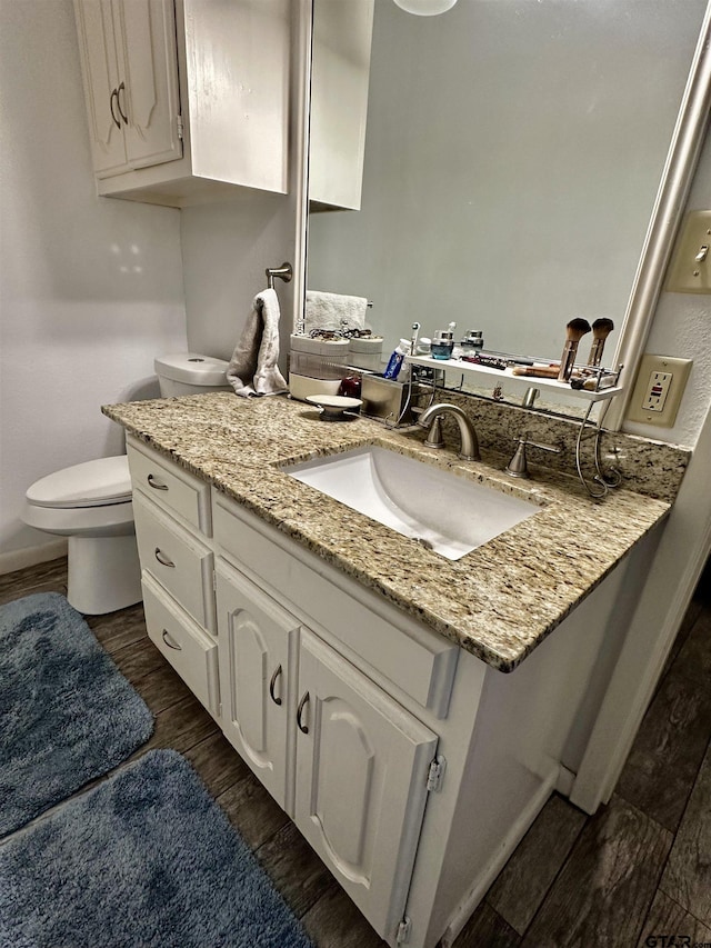 bathroom featuring vanity, hardwood / wood-style flooring, and toilet