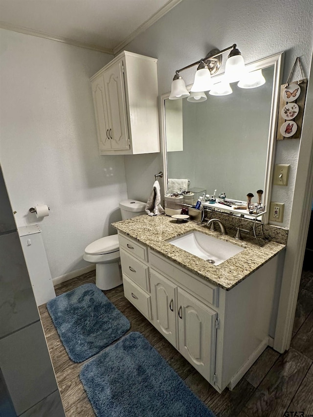 bathroom featuring hardwood / wood-style flooring, vanity, toilet, and ornamental molding