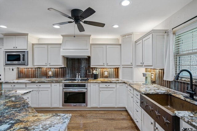 kitchen featuring white cabinets, hardwood / wood-style floors, sink, stone countertops, and appliances with stainless steel finishes