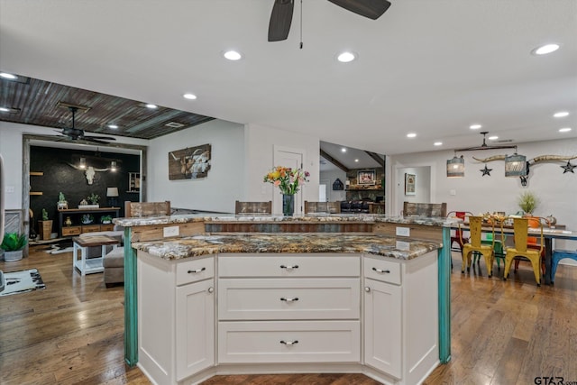 kitchen featuring white cabinets, stone countertops, hardwood / wood-style floors, and a center island