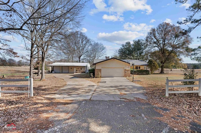 ranch-style house featuring a garage and a rural view