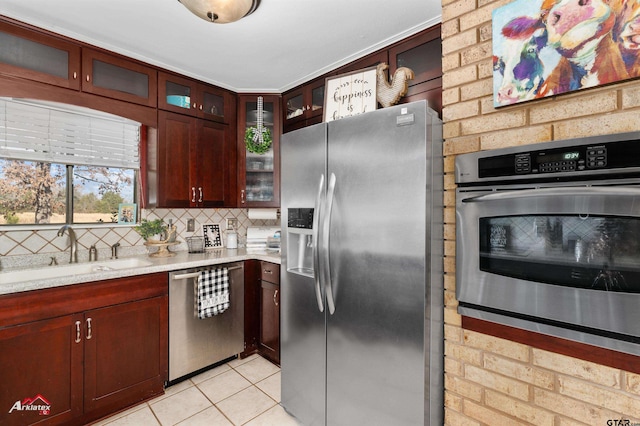 kitchen featuring appliances with stainless steel finishes, sink, backsplash, light tile patterned floors, and light stone counters