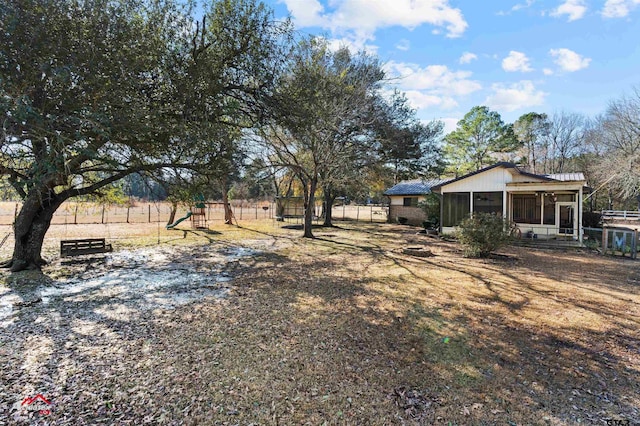 view of yard with a playground, a sunroom, and a rural view