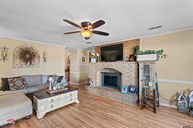 living room with hardwood / wood-style flooring, crown molding, a brick fireplace, and ceiling fan