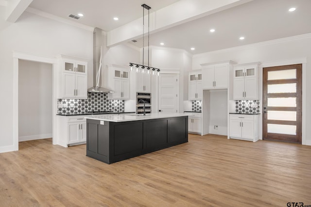 kitchen with white cabinetry, pendant lighting, and a center island with sink