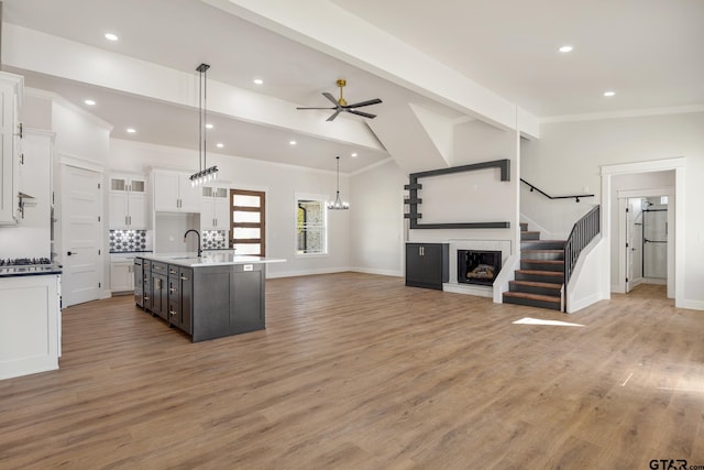 kitchen with a center island with sink, ceiling fan, white cabinetry, light wood-type flooring, and decorative light fixtures