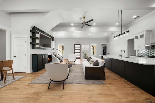 living room featuring crown molding, light hardwood / wood-style floors, sink, and ceiling fan