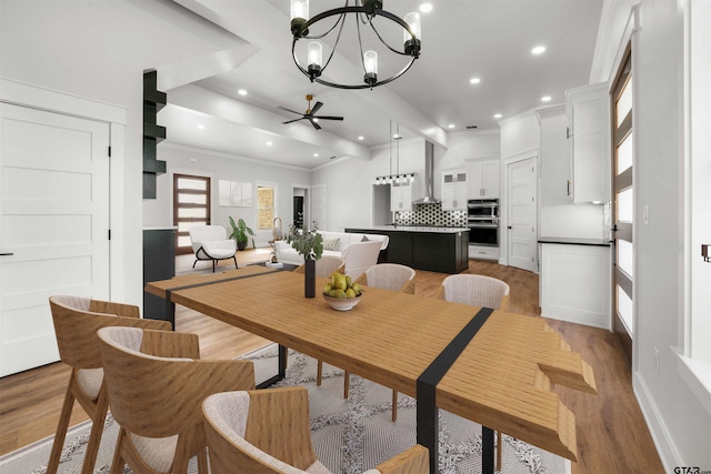 dining room with ceiling fan with notable chandelier, light hardwood / wood-style flooring, and crown molding