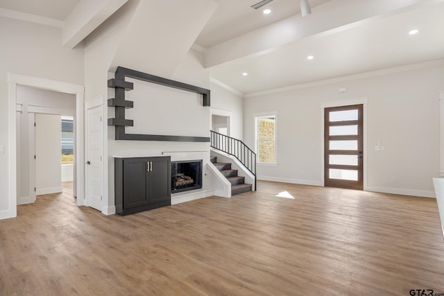 unfurnished living room with vaulted ceiling with beams, crown molding, and light hardwood / wood-style flooring