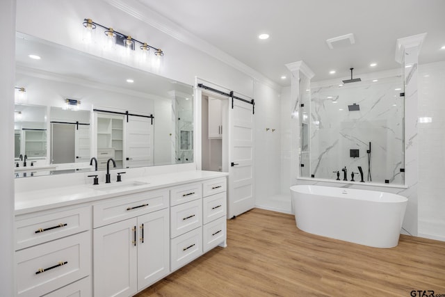 bathroom featuring vanity, shower with separate bathtub, hardwood / wood-style flooring, and ornamental molding