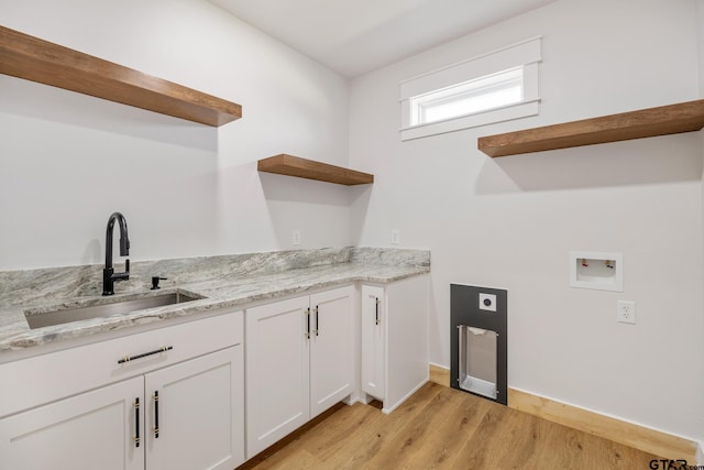 laundry area featuring washer hookup, cabinets, sink, and light hardwood / wood-style floors