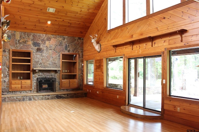 unfurnished living room with a fireplace, wood ceiling, wooden walls, and hardwood / wood-style floors