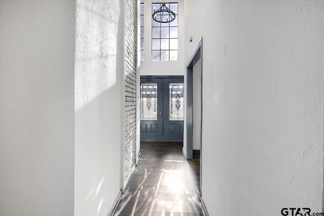 interior space with a high ceiling, a textured wall, wood finished floors, and baseboards