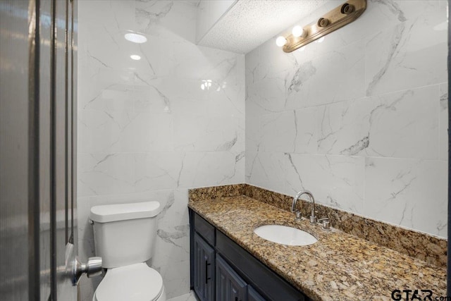 bathroom featuring toilet, vanity, and tile walls
