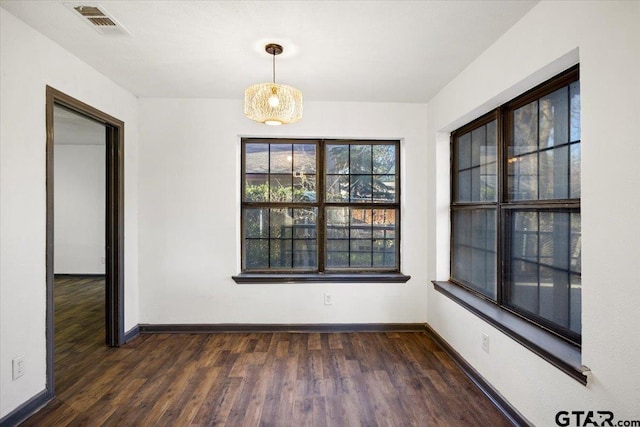unfurnished dining area featuring baseboards, dark wood-style flooring, and visible vents