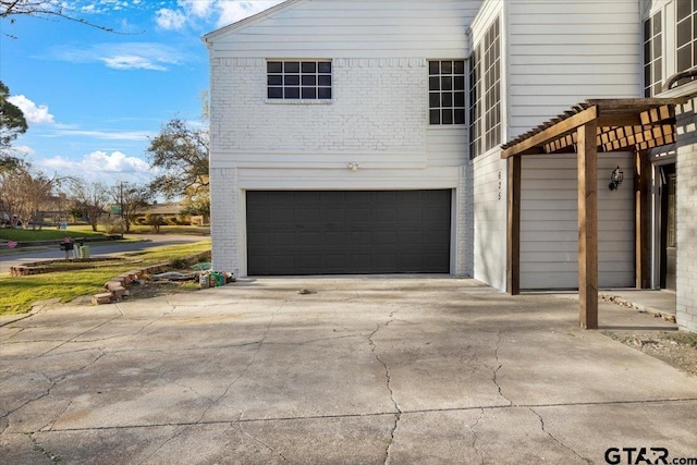 view of home's exterior featuring concrete driveway, an attached garage, and brick siding