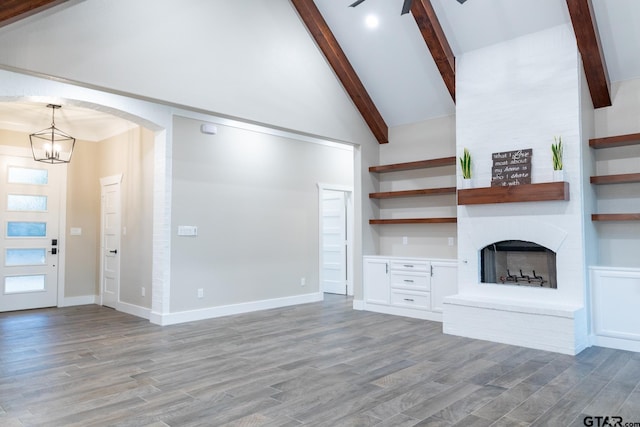 unfurnished living room featuring high vaulted ceiling, beamed ceiling, light wood-type flooring, and a fireplace