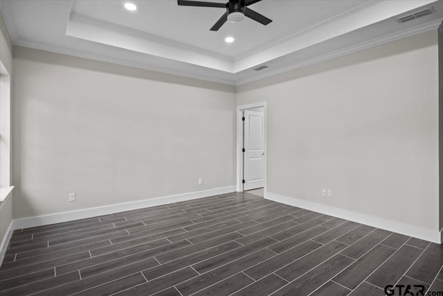 empty room featuring ceiling fan, crown molding, dark hardwood / wood-style flooring, and a tray ceiling