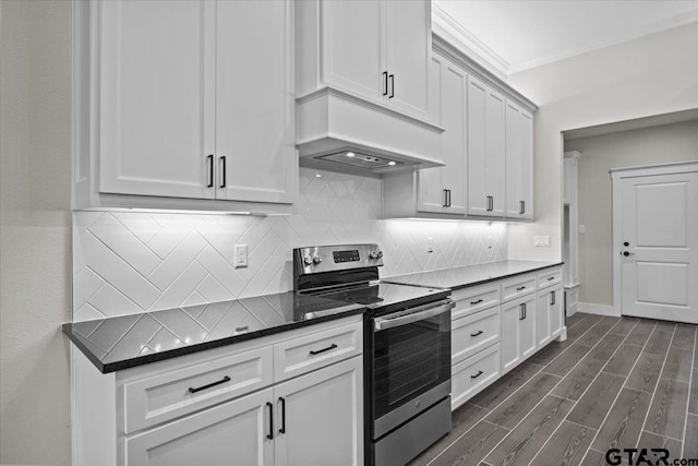 kitchen featuring stainless steel electric range, ornamental molding, dark hardwood / wood-style floors, white cabinetry, and premium range hood