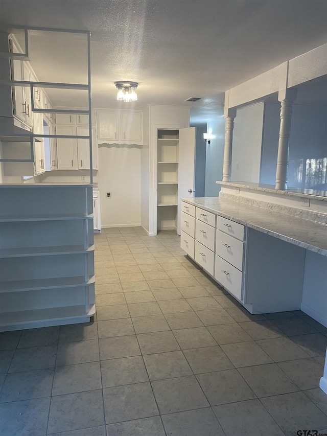 kitchen featuring white cabinets, light stone countertops, and light tile patterned floors