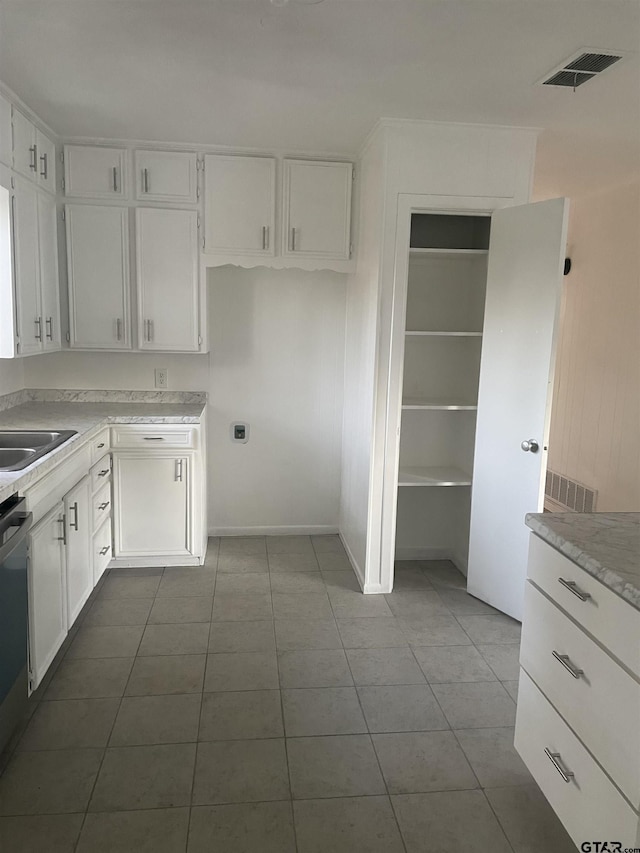 kitchen featuring sink, white cabinets, light tile patterned flooring, and dishwasher