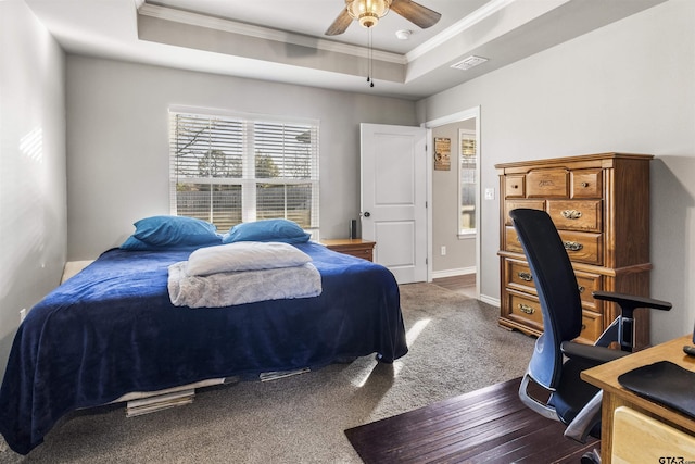 bedroom with dark colored carpet, a raised ceiling, ceiling fan, and crown molding