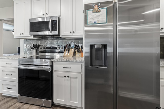 kitchen featuring light stone countertops, white cabinetry, backsplash, and appliances with stainless steel finishes