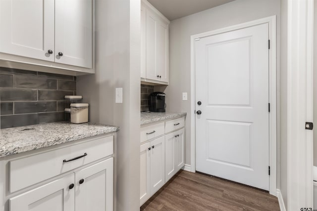 kitchen with backsplash, light stone countertops, dark hardwood / wood-style flooring, and white cabinets